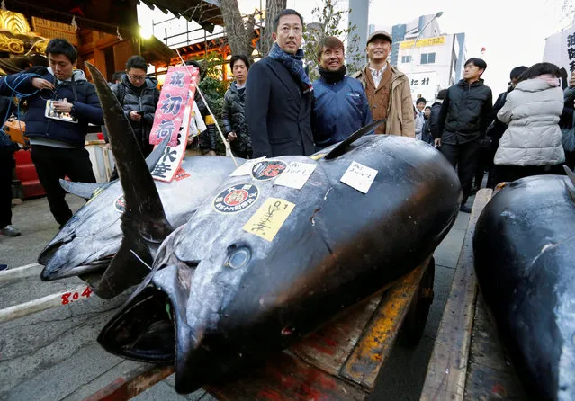 LEOC Co's Chairman, CEO and President Hiroshi Onodera (L of three men in the centre), who runs a chain of sushi restaurants, poses with a 405 kg bluefin tuna outside Tsukiji fish market in Tokyo, Japan, January 5, 2018. Onodera won the bid for the tuna caught off Oma, Aomori prefecture, northern Japan, with 36.45 million yen at the fish market's first tuna auction this year. (Photo by Toru Hanai/Reuters)