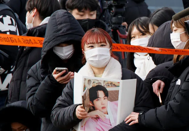 A fan holding a picture waits for the arrival of Jin, the oldest member of the K-pop band BTS, outside a South Korean army boot camp near the demilitarized zone separating the two Koreas, in Yeoncheon, South Korea on December 13, 2022. (Photo by Heo Ran/Reuters)