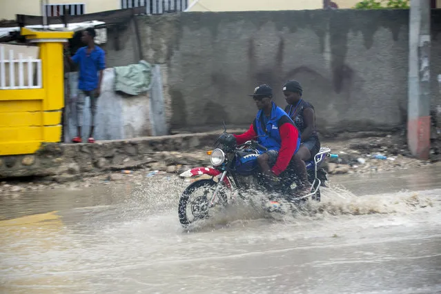 A moto-taxi driver moves through a street flooded by rain brought by the outer bands of Hurricane Isaias, in the Tabarre district of Port-au-Prince, Haiti, early Friday, July 31, 2020. Isaias kept on a path early Friday toward the U.S. East Coast as it approached the Bahamas. (Photo by Dieu Nalio Chery/AP Photo)