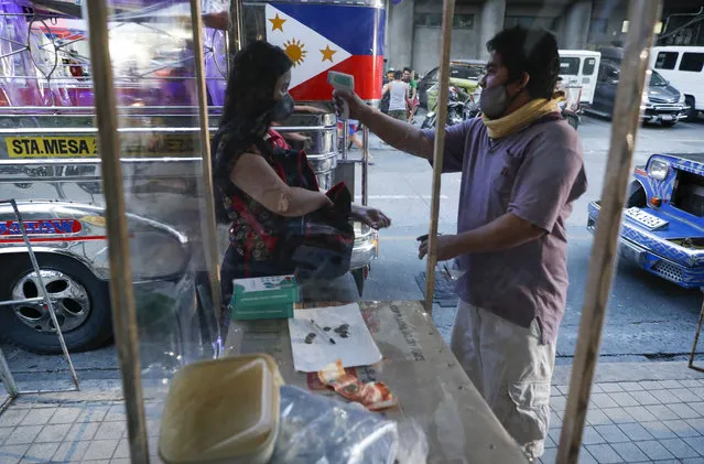 In this July 3, 2020, file photo, a passenger has her temperature checked to prevent the spread of the new coronavirus as some routes for the Traditional Jeepney buses were opened to help public transportation while the government slowly eases lockdown in metropolitan Manila, Philippines. The Philippines has seen a big recent spike in infections, raising the possibility its overcrowded capital may be placed back under a strict lockdown. (Photo by Aaron Favila/AP Photo/File)