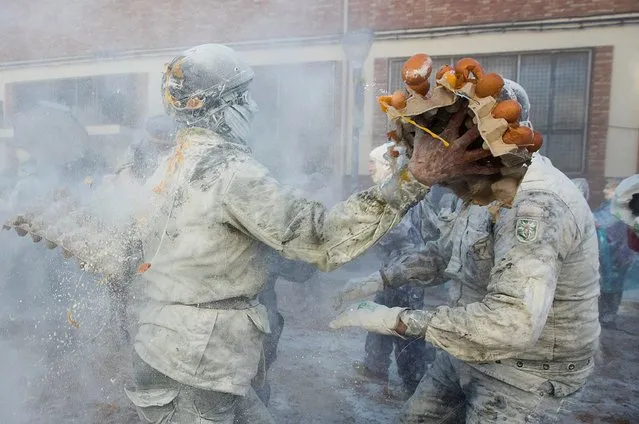 Revellers dressed in mock military garb take part in “Els Enfarinats” food-battle in the southeastern Spanish town of Ibi on December 28, 2022. In this 200-year-old traditional winter festival, the participants – known as Els Enfarinats (those covered in flour) – dress in military clothes and stage a mock coup d'etat as they battle using flour, eggs and firecrackers outside the city town hall as part of the celebrations of the Day of the Innocents, a traditional day in Spain for pulling pranks. (Photo by Jaime Reina/AFP Photo)
