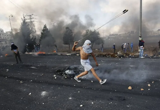 A Palestinian protester uses a sling to hurl stones towards Israeli troops during clashes near the Jewish settlement of Beit El, near the West Bank city of Ramallah October 9, 2015. (Photo by Mohamad Torokman/Reuters)