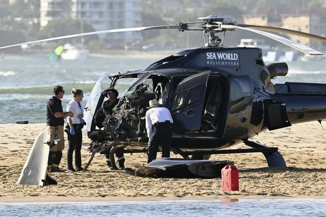 Emergency workers inspect a helicopter at a collision scene near Seaworld, on the Gold Coast, Australia, Monday, January 2, 2023. The 2 helicopters collided killing several passengers and critically injuring a few others in a crash that drew emergency aid from beachgoers enjoying the water during the southern summer. (Photo by Dave Hunt/AAP Image via AP Photo)