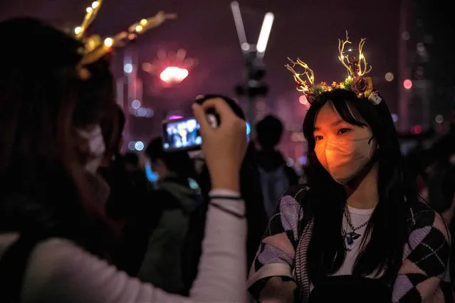 Revellers take photos during a fireworks and laser show as they celebrate the New Year next to Victoria Harbour in Hong Kong on January 1, 2023. (Photo by Isaac Lawrence/AFP Photo)