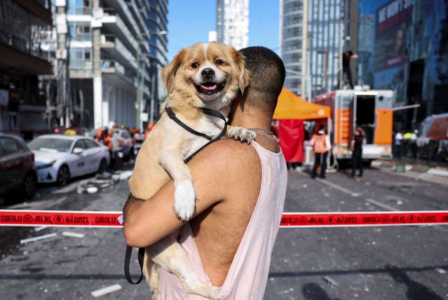 A person carries his dog as he stands at an impact site following a strike from Iran on Israel, in Ramat Gan, Israel on June 19, 2025. (Photo by Nir Elias/Reuters)