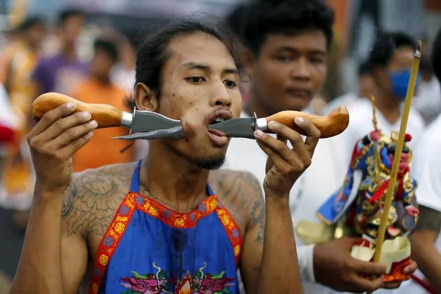 A devotee of the Chinese Samkong Shrine walks with knives pierced through his cheeks during a procession celebrating the annual vegetarian festival in Phuket, Thailand, October 16, 2015. (Photo by Jorge Silva/Reuters)