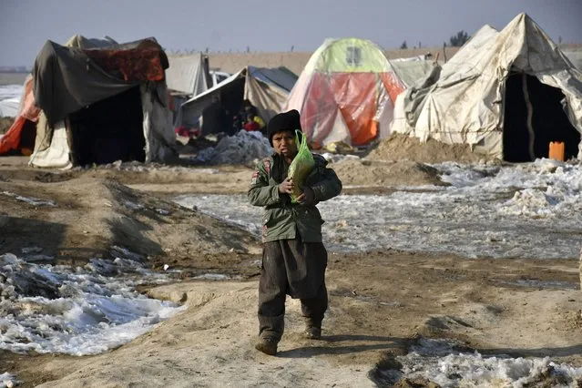 In this picture taken on January 17, 2023, an Afghan internally-displaced boy walks outside his during a cold winter day at the Nahr-e Shah-e- district of Balkh Province, near Mazar-i-Sharif. (Photo by Atif Aryan/AFP Photo)