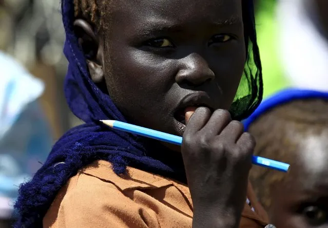 A girl waits to receive food provided by the United Nations' World Food Programme (WFP) during a visit by a European Union delegation, at an IDP camp in Azaza, east of Ad Damazin, capital of Blue Nile state, October 21, 2015. (Photo by Mohamed Nureldin Abdallah/Reuters)