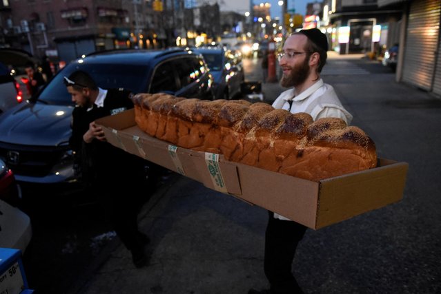 People carry an eight foot challah bread during celebrations to mark the Jewish holiday of Purim in the Brooklyn borough of New York City, U.S., March 6, 2023. (Photo by Stephanie Keith/Reuters)