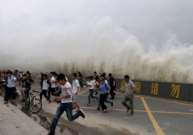 People run way from waves caused by a tidal bore which surged past a barrier on the banks of Qiantang River, in Hangzhou, Zhejiang province, China, October 3, 2016. (Photo by Reuters/Stringer)