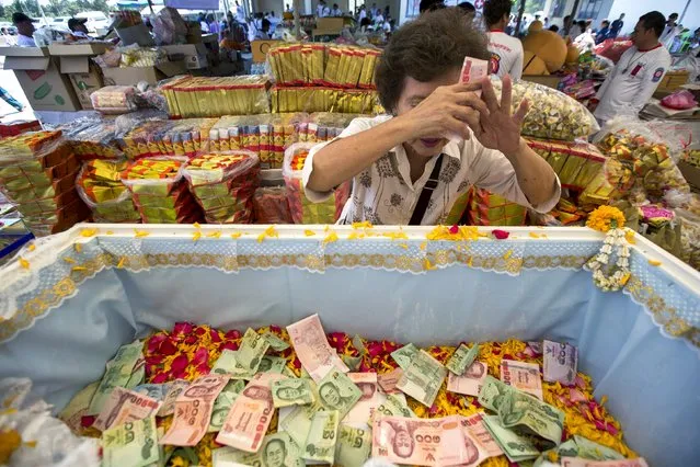 A woman pays her respects to the remains of unclaimed bodies during a buddhist ceremony at the Poh Teck Tung Foundation Cemetery in Samut Sakhon province, Thailand, November 11, 2015. (Photo by Athit Perawongmetha/Reuters)