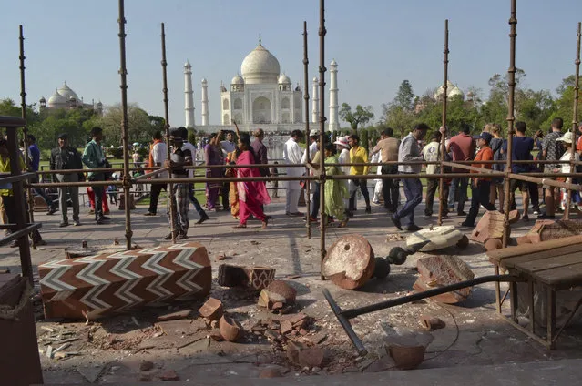 Tourists walk past the debris after a powerful storm Wednesday night toppled two minarets at the entry gates of the Taj Mahal monument in Agra, India, Thursday, April 12, 2018. (Photo by Pawan Sharma/AP Photo)