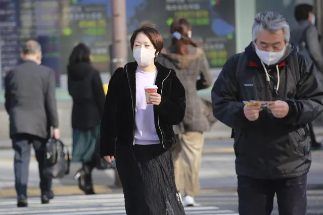 People wearing face masks to protect against the spread of the coronavirus walk on the street in Tokyo, Monday, December 14, 2020. (Photo by Koji Sasahara/AP Photo)