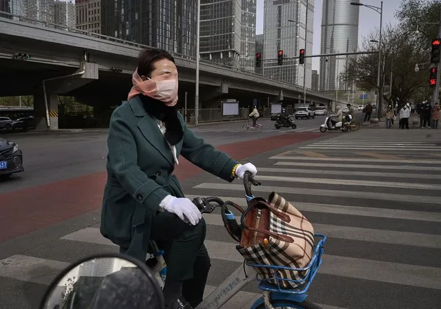 A woman wears a mask and scarf over her face as she rides a shared bike during a sandstorm on April 11, 2023 in Beijing, China. China's capital and the northern part of the country typically experience sandstorms that originate in the Gobi desert, but scientists believe that climate change and desertification also play an increasing role in their frequency and intensity. (Photo by Kevin Frayer/Getty Images)