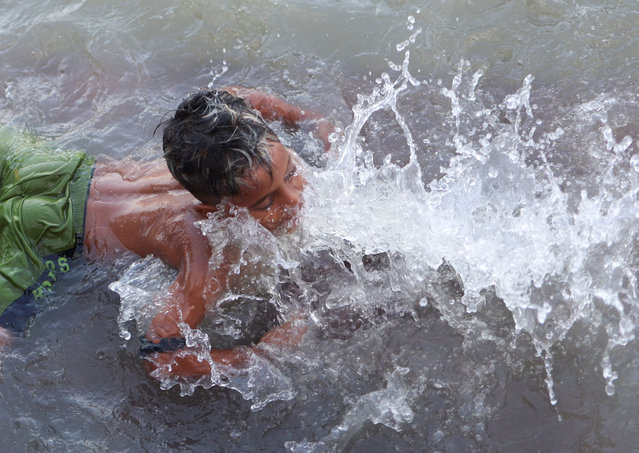 A boy plays with water as he bathes in the river Ganges in Kolkata, India, on September 29, 2025. (Photo by Sahiba Chawdhary/Reuters)