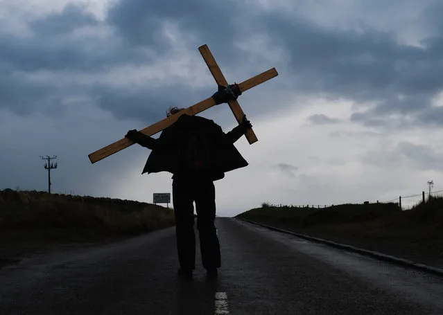 Pilgrims celebrate Easter by crossing over the tidal causeway carrying wooden crosses on the final leg of their annual pilgrimage to the Holy Island of Lindisfarne on March 30, 2018 in Berwick-upon-Tweed, England. Around 100 people of all ages and backgrounds celebrated Easter by crossing at low tide during the pilgrimage which ends on the island. The event is organised by Northern Cross and sees pilgrims walking between 70 to 120 miles in the week leading up to the Good Friday crossing. (Photo by Ian Forsyth/Getty Images)