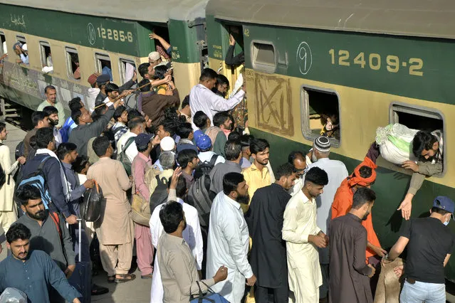 People board a passenger train to reach their villages and cities to celebrate the upcoming Eid al-Fitr holidays, marking the end of the Islamic holy month of Ramadan, in Lahore, Pakistan, Thursday, April 20, 2023. (Photo by Pervez Masih/AP Photo)