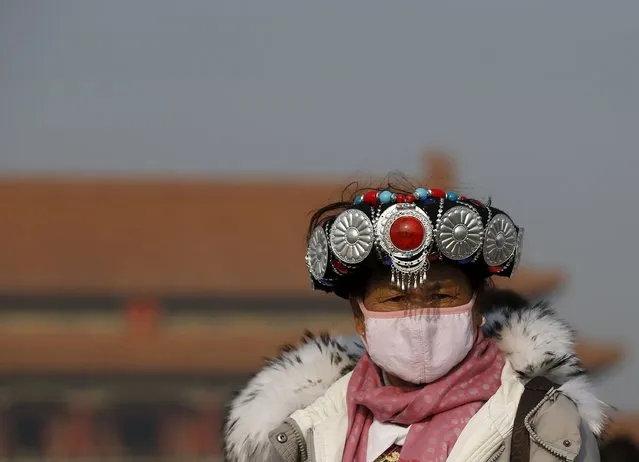 An ethnic minority woman, wearing a mask and seen in a traditional costume, visits the Tiananmen Square during a heavily polluted day in Beijing, China, November 29, 2015. Beijing plans to ramp up its already tough car emission standards by 2017 in a bid by one of the world's most polluted cities to improve its often hazardous air quality. (Photo by Kim Kyung-Hoon/Reuters)