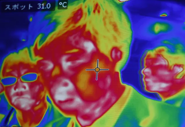 A screen shows visitors filmed with the FLIR GF320 Infrared Camera at the System Control Fair SCF 2015 in Tokyo, Japan December 2, 2015. (Photo by Thomas Peter/Reuters)