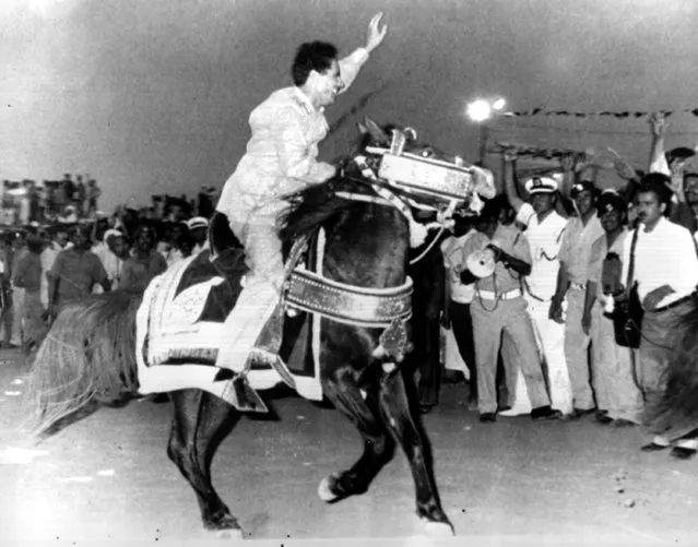 Col. Moammar Gadhafi, president of Libya, waves to a crowd as he rides a horse during a ceremony in Ajdabia, Libya, on October 10, 1976. The celebration marks the sixth anniversary of the eviction of Italians from Libya. (Photo by AP Photo)