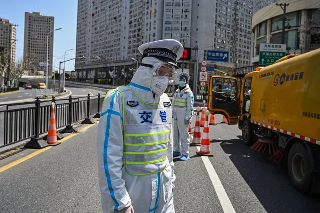 Transit officers, wearing a protective gear, control access to a bridge in the direction of Pudong district in lockdown as a measure against the Covid-19 coronavirus, in Shanghai on March 29, 2022. (Photo by Hector Retamal/AFP Photo)