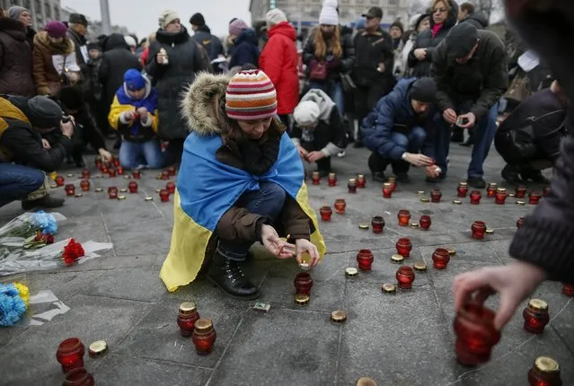 People light candles during a peace march in Kiev January 18, 2015, for the victims on a passenger bus which came under fire near the town of Volnovakha in eastern Ukraine. The bus came under heavy fire on January 13, killing at least 10 people, Ukrainian authorities said, and fighting intensified around the international airport in the city of Donetsk as separatists tried to oust government forces. (Photo by Gleb Garanich/Reuters)