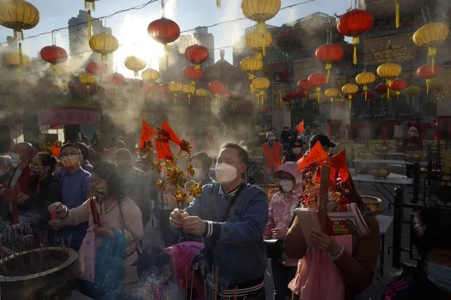 Worshippers wearing face masks to protect against the spread of the coronavirus burn joss sticks as they pray at the Wong Tai Sin Temple, in Hong Kong, Friday, February 12, 2021, to celebrate the Lunar New Year which marks the Year of the Ox in the Chinese zodiac. (Photo by Kin Cheung/AP Photo)