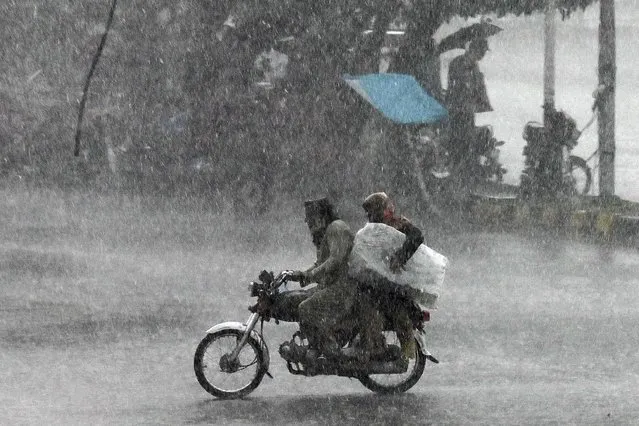 Motorcyclists ride a motorbike along a street during a rainfall in Lahore on June 6, 2023. (Photo by Arif Ali/AFP Photo)