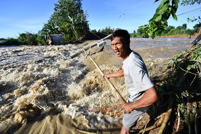 A resident tries to catch fish along a burst river dike destroyed during Super Typhoon Man-yi at a farming village in Aliaga, Nueva Ecija province, Philippines on November 19, 2024. (Photo by Ted Aljibe/AFP Photo)