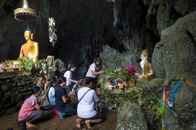 Family members pray before a shrine in Tham Luang cave area as operations continue for the 12 boys and their coach trapped at the cave at Khun Nam Nang Non Forest Park in the Mae Sai district of Chiang Rai province on July 5, 2018. Thai rescuers vowed to take a “no risk” approach to freeing 12 boys and their football coach from a flooded cave, as fresh video emerged on July 4 showing the team in good spirits following their astonishing discovery nine days after going missing. (Photo by Ye Aung Thu/AFP Photo)