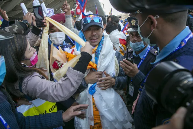 Nirmal Purja one of the team member of the all-Nepalese mountaineering team that became the first to scale Mount K2 in winter receives a scarf as they arrive at Tribhuwan International airport in Kathmandu, Nepal, Tuesday, January 26, 2021. (Photo by Niranjan Shrestha/AP Photo)