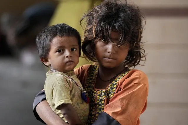 A girl holds her younger brother as she with her family take shelter in a school after fleeing from their villages of costal areas due to Cyclone Biparjoy approaching, in Gharo near Thatta, a Pakistan's southern district in the Sindh province, Wednesday, June 14, 2023. In Pakistan, despite strong winds and rain, authorities said people from vulnerable areas have been moved to safer places in southern Pakistan's districts. With Cyclone Biparjoy expected to make landfall Thursday evening, coastal regions of India and Pakistan are on high alert. (Photo by Fareed Khan/AP Photo)