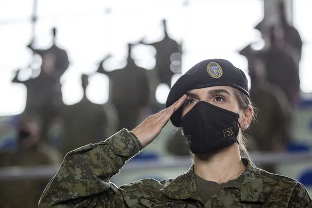 A Kosovo Security Force (KSF) member wearing a face mask salutes, during a peacekeeping mission deployment ceremony held at the army barracks in Pristina, Tuesday, March 9, 2021. Kosovo is sending a military platoon to Kuwait, its first ever involvement in an international peacekeeping mission. A ceremony was held Tuesday at the army barracks in the capital, Pristina, with the presence of top country leaders and western military attaches. Kosovo is sending the military unit following a request from the U.S. Central Command. (Photo by Visar Kryeziu/AP Photo)