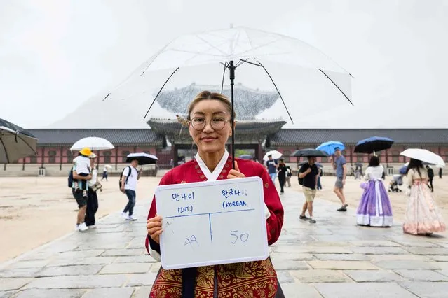 In this picture taken in Seoul on June 21, 2023, Kim Min, a South Korean living in Australia, poses with a whiteboard showing her international age, 49, and Korean age, 50. From June 28, 2023  South Korea will use the international system that calculates age according to a person's actual date of birth, meaning everyone will officially become a year or two younger. (Photo by Anthony Wallace/AFP Photo)