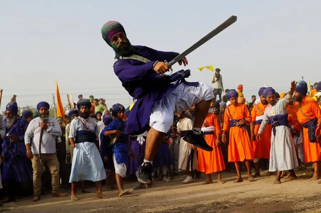 A Nihang, or a Sikh warrior, performs “Gatkha”, a traditional form of martial arts during celebrations of Hola Mohalla, a festival of Nihangs, during Holi celebrations, at the site of a protest against farm laws, at Singhu border near New Delhi, India, March 29, 2021. (Photo by Adnan Abidi/Reuters)