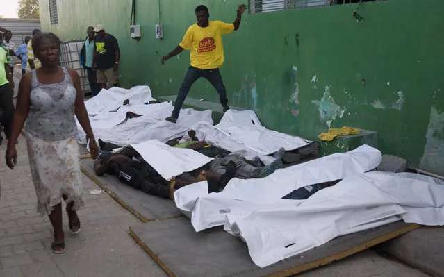 A woman walks away from bodies after failing to find a missing family member among them outside the morgue at the General Hospital in Port-au-Prince, Haiti, Tuesday, February 17, 2015. At least 20 people were killed early Tuesday after a man on top of a musical group's Carnival float was electrocuted, setting off a panic in which dozens of people were trampled, witnesses and officials said. (Photo by Dieu Nalio Chery/AP Photo)