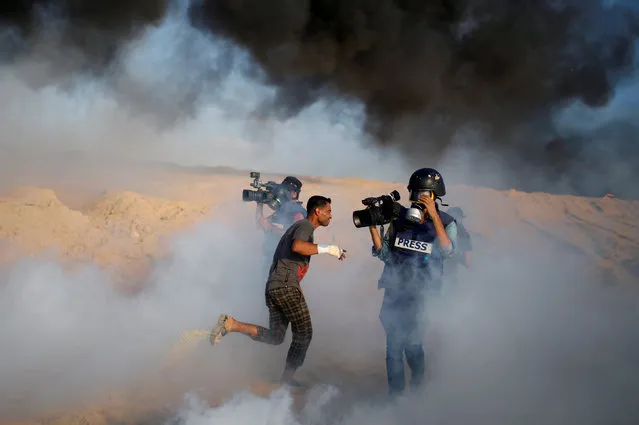 Cameramen film as a Palestinian demonstrator reacts to tear gas fired by Israeli troops during a protest calling for lifting the Israeli blockade on Gaza, on a beach near the maritime border with Israel, in the northern Gaza Strip September 10, 2018. (Photo by Mohammed Salem/Reuters)