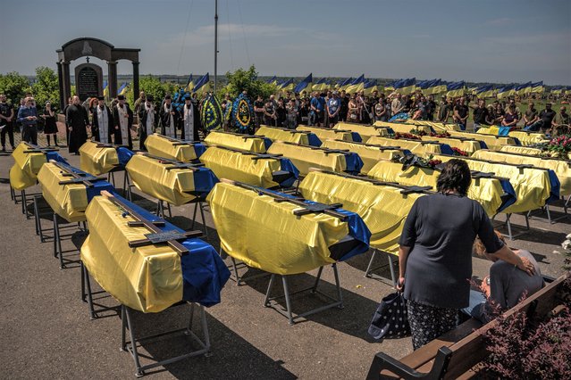 The funeral ceremony for 27 Ukrainian serviceman who died fighting with the Russians in the eastern front-line, in the military part of Krasnopilske cemetery in Dnipro, Ukraine, on June 3, 2022. 12 of the Ukrainian soldiers were buried unidentified. (Photo by Wojciech Grzedzinski/The Washington Post)