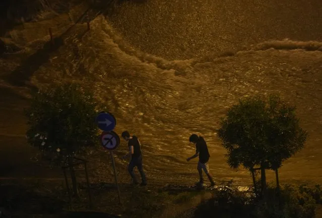 People walk next to floodwaters blocking the road due to the heavy rain in Basaksehir district of Istanbul, Turkey, Tuesday, September 5, 2023. Flash floods triggered by heavy rains swept through a campsite in northwest Turkey on Tuesday, killing at least two people, officials said. Four other people were reported missing. (Phoot by Khalil Hamra/AP Photo)