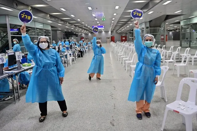 Health workers call for people to receive doses of the Covid-19 coronavirus CoronaVac vaccine at Bang Sue Central Station in Bangkok on May 24, 2021. (Photo by Lillian Suwanrumpha/AFP Photo)