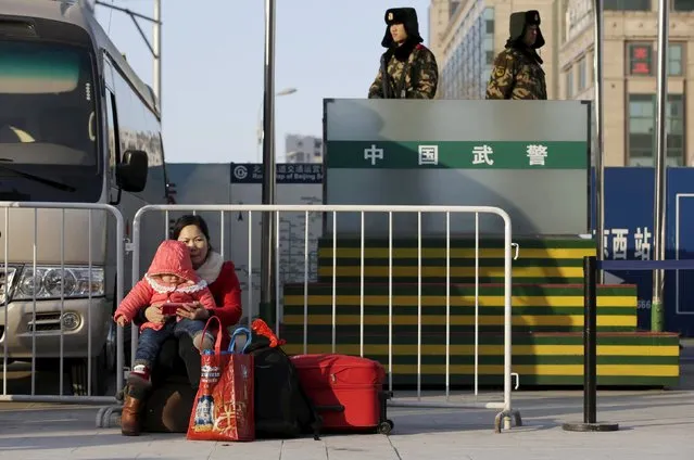 A one-year-old girl and her mother wait for their train next to paramilitary policemen at Beijing Railway Station, in Beijing, China, January 25, 2016. (Photo by Jason Lee/Reuters)