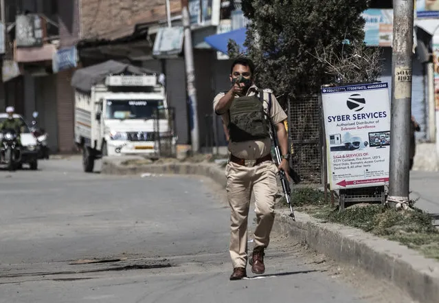 A policeman gestures towards the media near the site of a shootout at Sopore, 55 kilometers (34 miles) north of Srinagar, Indian controlled Kashmir, Saturday, June 12, 2021. (Photo by Mukhtar Khan/AP Photo)