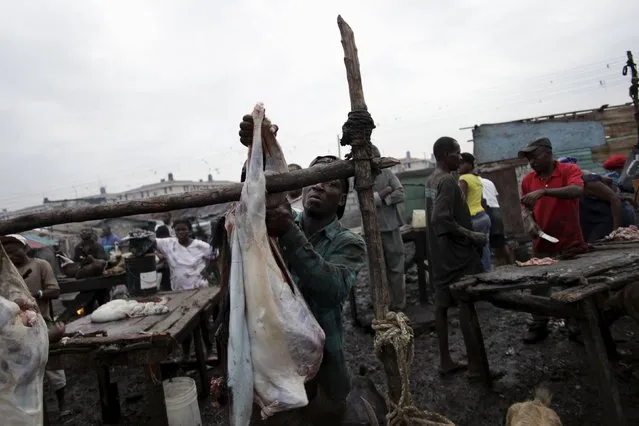 Jean Libonet hangs a butchered goat to be sold at La Saline slaughterhouse in Port-au-Prince, Haiti, March 19, 2015. (Photo by Andres Martinez Casares/Reuters)