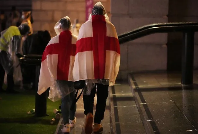 England supporters wear flags as they leave the designated fan zone at Trafalgar Square in London, Sunday, July 11, 2021, after Italy won the Euro 2020 soccer championship final match between England and Italy played at Wembley Stadium. (Photo by Matt Dunham/AP Photo)