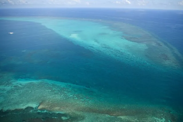 This photo taken on September 28, 2023 shows an aerial view of the mouth of the Chinese-controlled Scarborough Shoal, seen without any barriers obstructing the passageway, as Chinese coast guard ships (top L) are seen anchored inside the lagoon of the Chinese-controlled Scarborough Shoal during a maritime surveillance flight by the Philippine Bureau of Fisheries and Aquatic Resources (BFAR) over disputed waters of the South China Sea.  (Photo by Ted Aljibe/AFP Photo)
