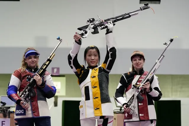 Yang Qian, of China, holds her rifle aloft after winning a gold medal in the women’s 10-meter air rifle at the Asaka Shooting Range in the 2020 Summer Olympics, Saturday, July 24, 2021, in Tokyo, Japan. Anastasiia Galashina, left, of the Russian Olympic Committee, took the silver medal and Nina Christen, of Switzerland took the bronze medal. (Photo by Alex Brandon/AP Photo)