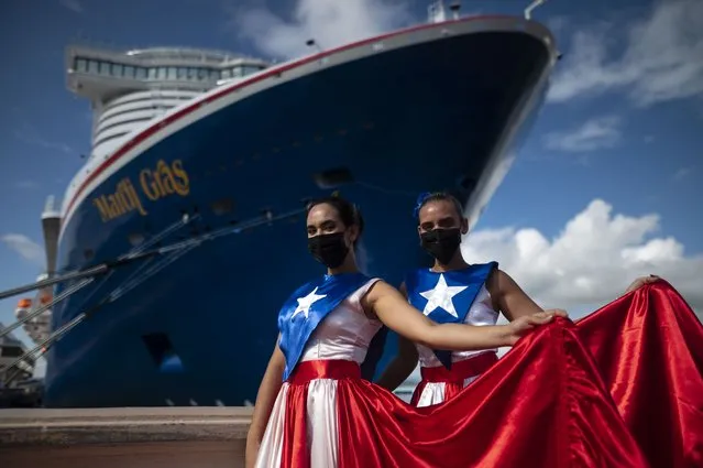 Ivanelis Jimenez, front, and Veronica Barreto pose for the camera wearing Puerto Rican flag dresses as they welcome passengers exiting Carnival's Mardi Gras cruise ship, docked in the bay of San Juan, Puerto Rico, Tuesday, August 3, 2021, marking the first time a cruise ship visits the U.S. territory since the COVID-19 pandemic began. (Photo by Carlos Giusti/AP Photo)