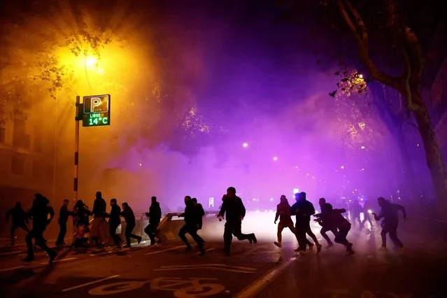 Demonstrators run next to riot police during a protest near Spain's Socialists Party (PSOE) headquarters, after Spain's socialists reached a deal with the Catalan separatist Junts party for government support, a pact which involves amnesties for people involved with Catalonia's failed 2017 independence bid, in Madrid, Spain on November 11, 2023. (Photo by Susana Vera/Reuters)