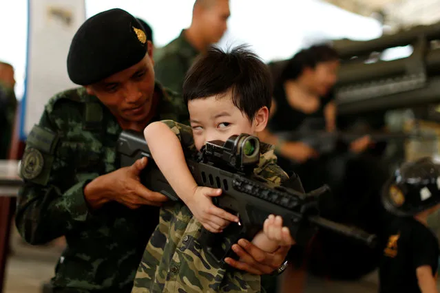 A Thai army soldier gives a weapon to a boy to pose for a picture during Children's Day celebration at a military facility in Bangkok, Thailand January 14, 2017. (Photo by Jorge Silva/Reuters)