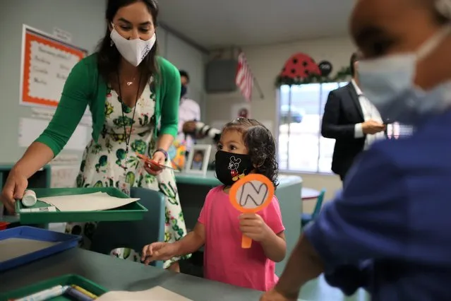 Teacher Tanya Ortiz Franklin helps Natalia Castillo on the first day back at school for LAUSD students following the COVID-19 coronavirus disease remote school period, in Harbor City, Los Angeles, California, U.S., August 16, 2021. (Photo by Lucy Nicholson/Reuters)